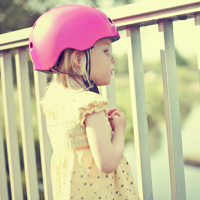 Girl standing in front of a fence while wearing a Pink Melon Bicycle Helmet