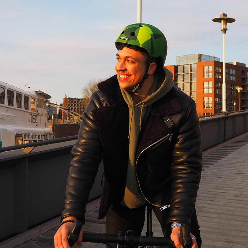 Man riding his bike by the docks wearing a Melon Green Mamba Bike Helmet