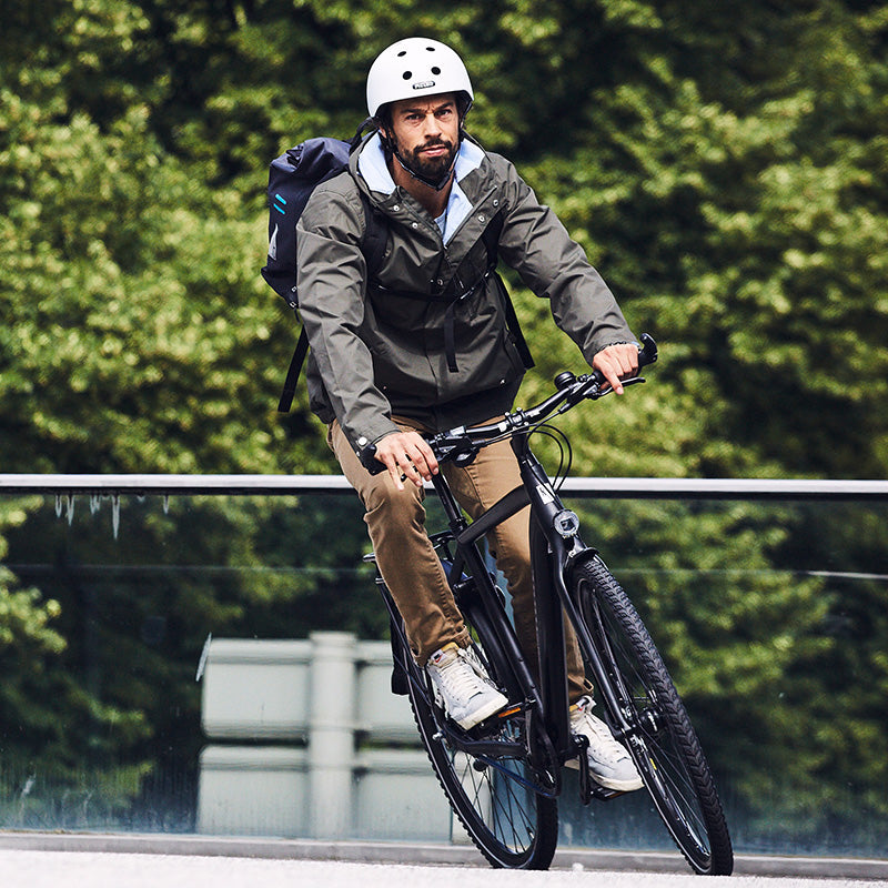 Man riding his bike in front of trees in Hamburg while wearing a Melon "Brightest" Bicycle Helmet