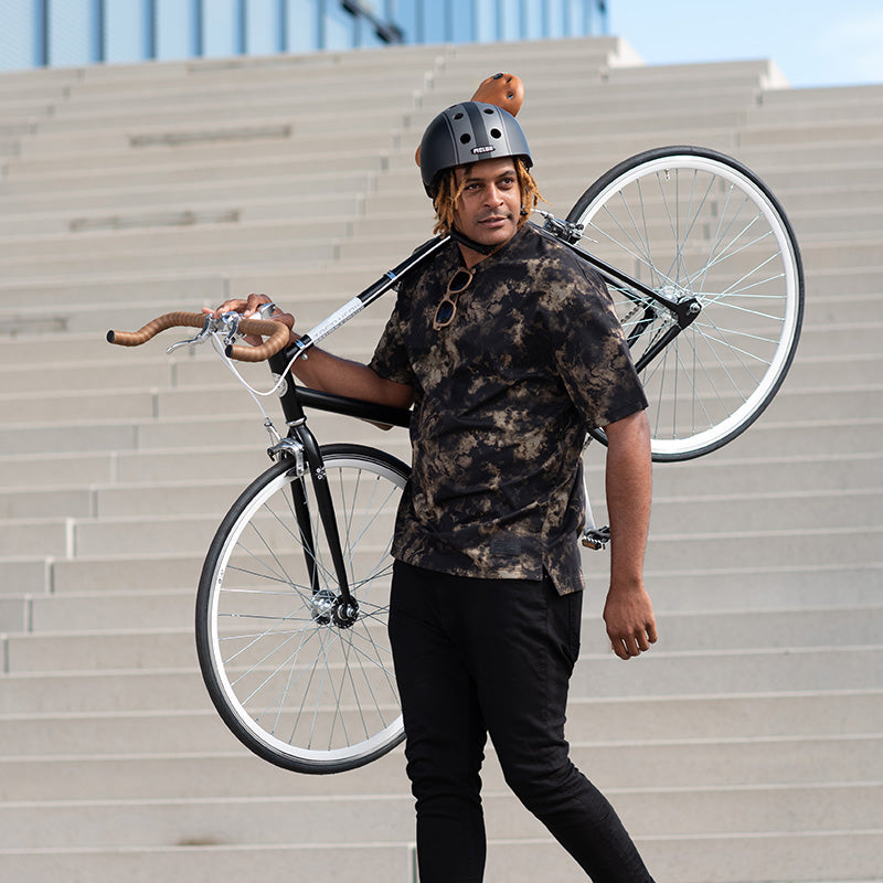 Man holding his Bike on his Shoulders while wearing a Melon Decent Double Black Bicycle Helmet