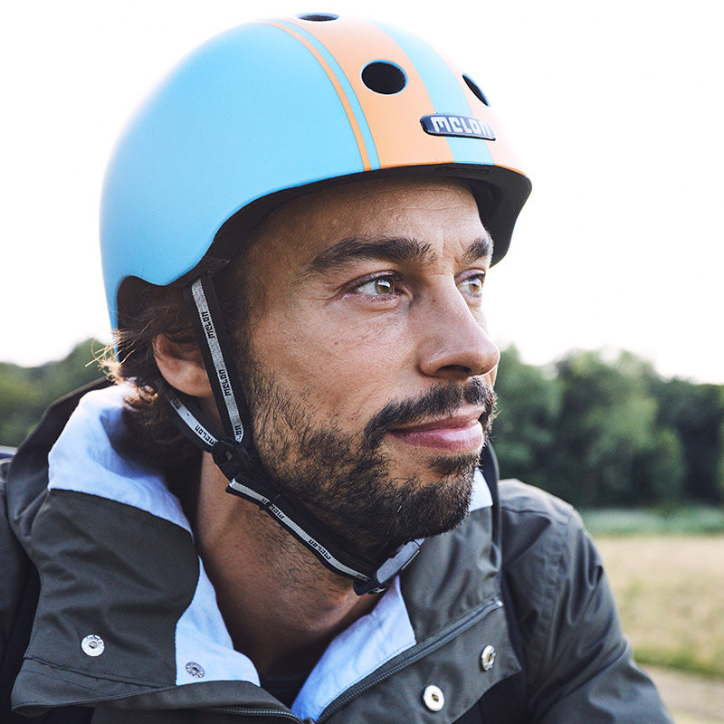 Man standing in nature wearing a Melon Double Orange Blue Bicycle Helmet