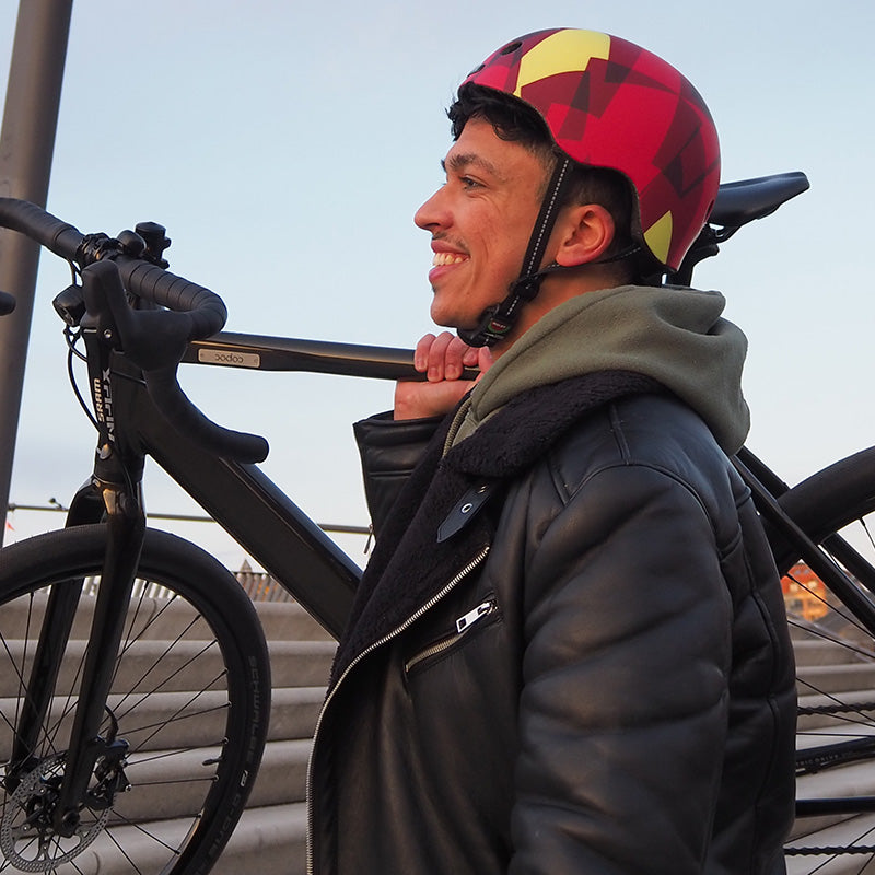 Man holding his bike over his shoulder while wearing a Melon Urban Active "Ember" Bicycle Helmet