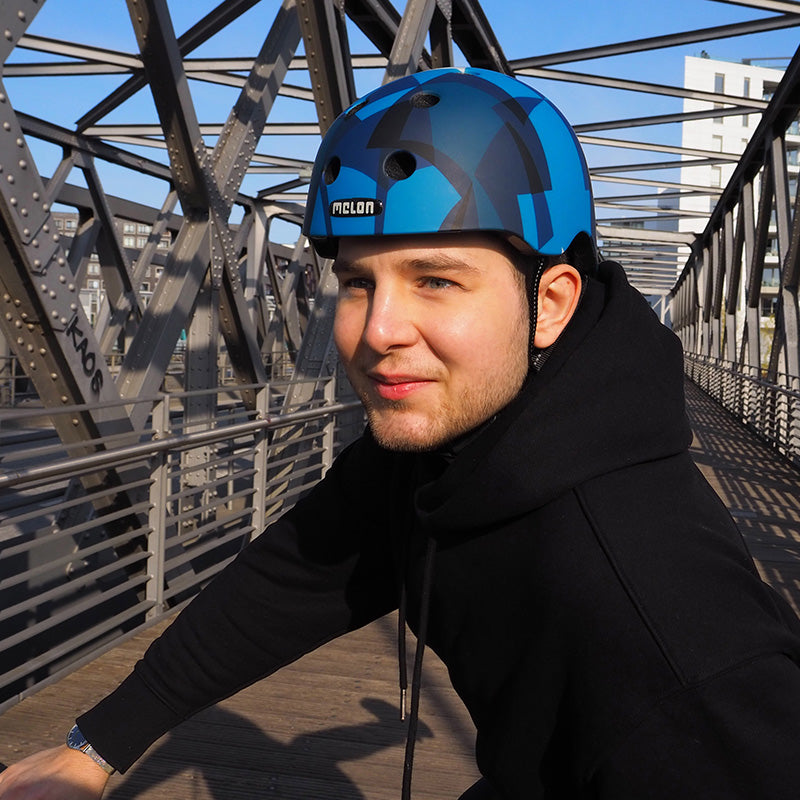 Man wearing a Melon Frozen Lake Bicycle Helmet on a bridge