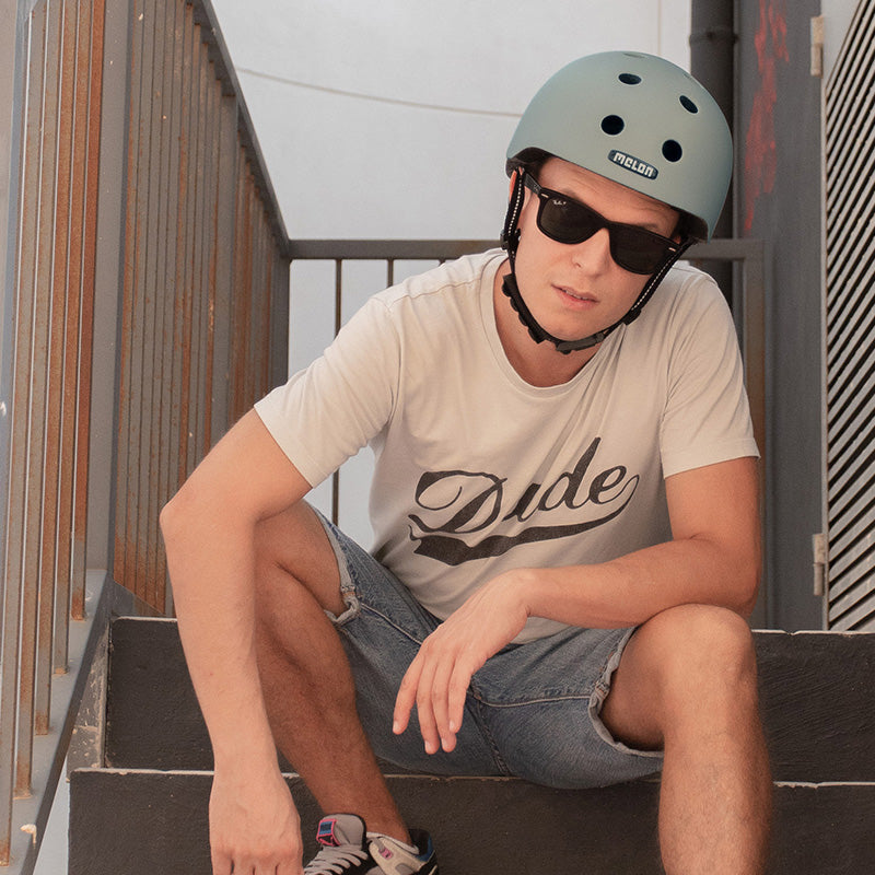 Man with sunglasses posing on stairs wearing a grey Melon New York Helmet