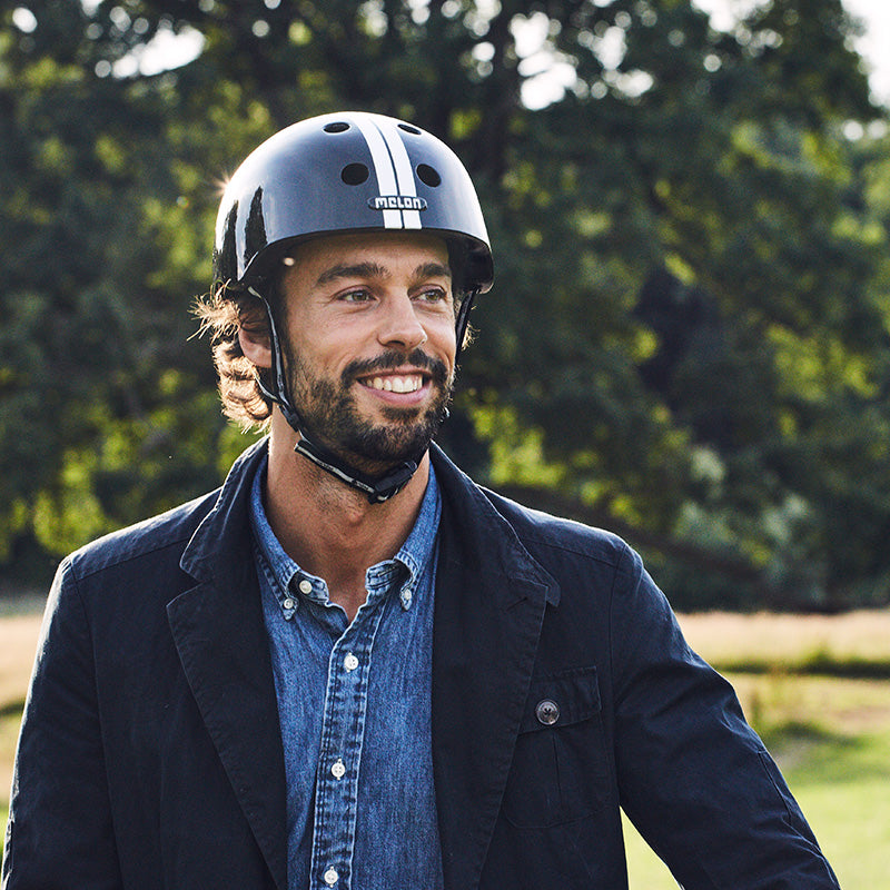 Man in nature wearing a black Melon Bicycle Helmet with white stripes