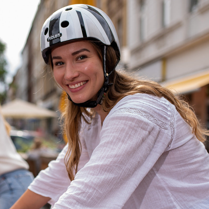 Girl riding her bicycle through the city wearing a Union Jack Plain Bicycle Helmet